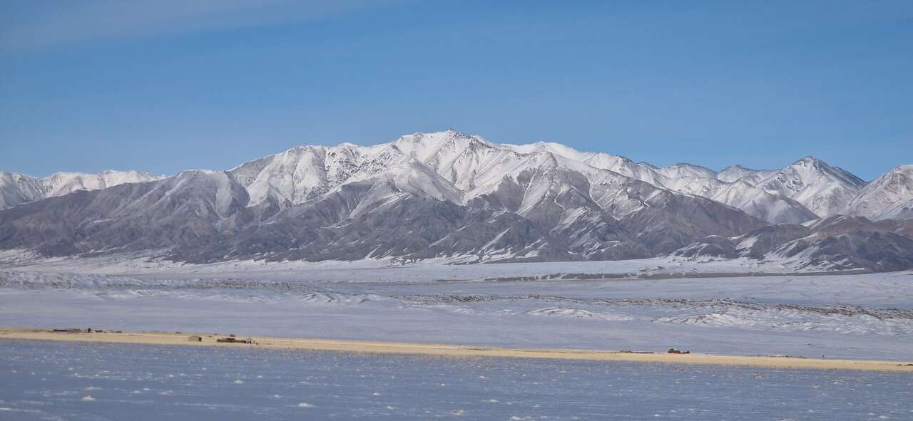 Panorama des montagnes enneigées de l'Altaï mongol dominant une vaste plaine en hiver