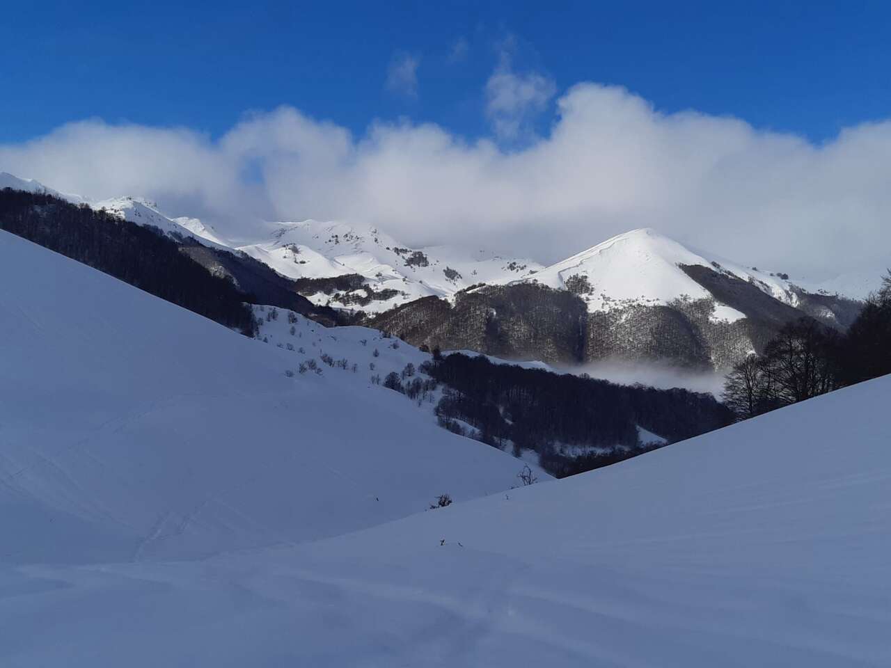 Paysage de montagnes enneigées sous un ciel bleu dans les Abruzzes en hiver – randonnée naturaliste avec Amarok l’Esprit Nature