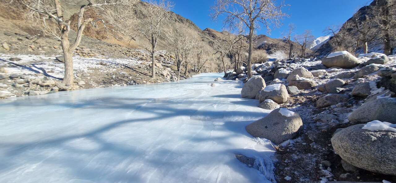Rivière gelée traversant une vallée rocheuse enneigée dans les montagnes de l'ouest de la Mongolie