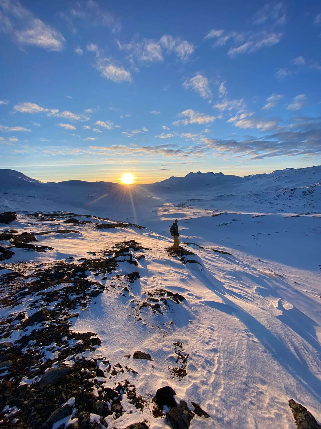 Skieur sur les hauteurs enneigées du Storstein au coucher du soleil