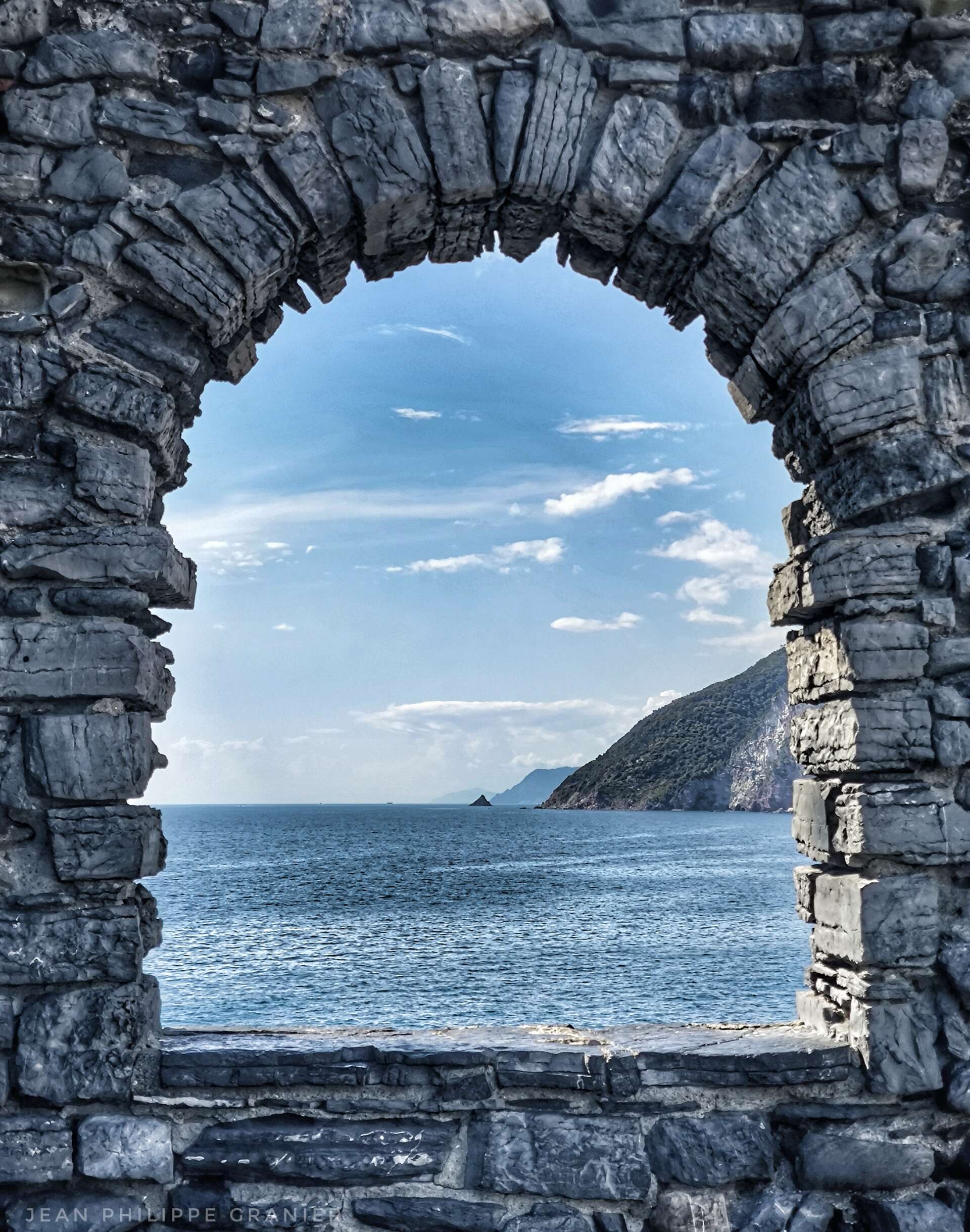 Vue sur la Méditerranée à travers une arche en pierre sur le sentier des Cinque Terre